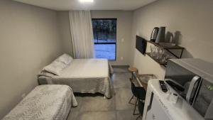 a small room with two beds and a window at Villa Parati Bombinhas Sob Nova Direção in Bombinhas