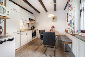 a kitchen with white cabinets and a table and chairs at Ferienwohnung Spatzennest in Arrach