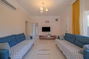 a living room with blue couches and a television at Villa Ata Park Ortaca in Ortaca