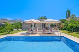 a pool with chairs and umbrellas next to a house at Villa Ata Park Ortaca in Ortaca