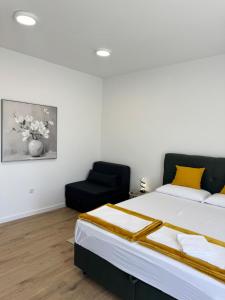 a bedroom with a bed and a black chair at Studio Sanja in Vlašići