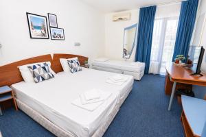 a hotel room with two beds and a desk at Hotel M2 in Primorsko +23 photos