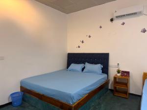 a bedroom with a bed with blue sheets and a nightstand at Afaa Beach Guest House in Arugam Bay