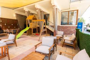 a patio with a slide and chairs and a playground at Hotel M2 in Primorsko