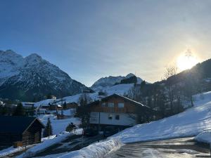 a village covered in snow with the sun in the background at Ferienwohnung Kleinwalsertal in Hirschegg +5 photos
