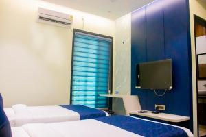 a hotel room with two beds and a television at Hotel Orbit in Parbhani