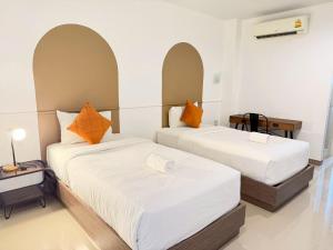 two beds in a room with white walls and orange pillows at The S Design Hotel in Buriram