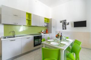 a kitchen with a table and some green chairs at Villa Anny Fronte Mare in Avola