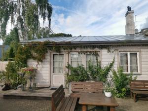 a small white house with a table and benches at Beguta Guest House in Haapsalu