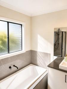 a white bath tub in a bathroom with a window at Modern Family Home in Truganina - Space to Relax in Truganina