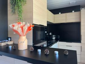 a kitchen with a black counter with a vase with flowers at CHALET 10 chaleureux tout confort dans domaine avec Piscine au cœur des Landes bord de Lac avec plage aménagée in Labouheyre +22 photos