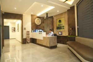 a man sitting at a counter in a lobby at Hotel Orbit in Parbhani