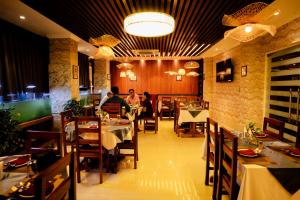 a dining room with people sitting at tables in a restaurant at Hotel octavia in Imphal +9 photos