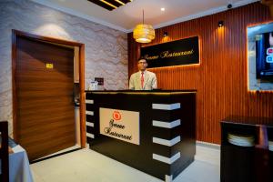 a man standing behind a counter in a restaurant at Hotel octavia in Imphal