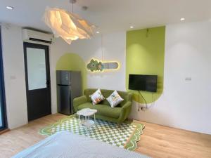 a living room with a green couch and a tv at Little House Đông Tác in Hanoi