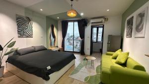 a bedroom with a bed and a green couch at Little House Đông Tác in Hanoi