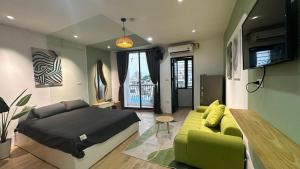 a bedroom with a bed and a green couch at Little House Đông Tác in Hanoi