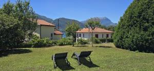 two chairs sitting in the grass in front of a house at Luna in Lierna