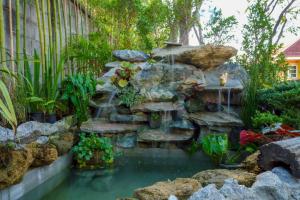 a garden with a waterfall and a fish pond at After Beach House Phla Resort in U-Tapao +5 photos