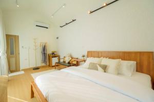 a bedroom with a large white bed with a wooden headboard at After Beach House Phla Resort in U-Tapao
