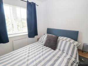 a bedroom with a bed with a blue headboard and a window at 7 Cwrt Y Cadno in Llantwit Major
