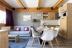 a kitchen and living room with a table and chairs at Résidence Odalys Le Pelvoux in La Plagne