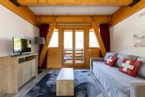 a living room with a couch and a tv at Résidence Odalys Le Pelvoux in La Plagne