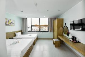 a hotel room with two beds and a tv at Cherry Airport Hotel and Apartment 2 in Ho Chi Minh City +39 photos