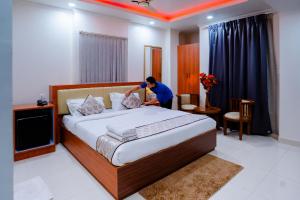 a man putting pillows on a bed in a hotel room at Hotel octavia in Imphal
