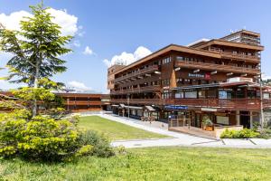 a large building with a tree in front of it at Résidence Odalys Le Pelvoux in La Plagne