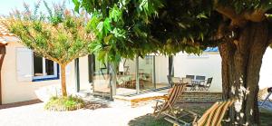 a house with a patio with chairs and trees at La Pause Jardaise in Jard-sur-Mer