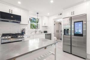 a kitchen with white cabinets and a stainless steel refrigerator at Steps to the Beach Cozy Central AC in Yarmouth