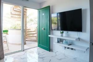 a living room with a green door and a television at Rayito de sol 3 in Costa de Antigua