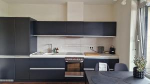 a kitchen with black and white cabinets and a table at Modern skyline-view condo at a luxury complex in Vilnius