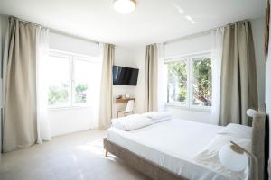 a white bedroom with a bed and two windows at Corte Fossalta - Casa Linda in Lazise