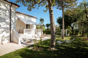 a white house with a porch and a tree at Corte Fossalta - Casa Linda in Lazise