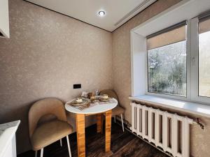 a dining room with a table and chairs and a window at Квартира in Temirtaū