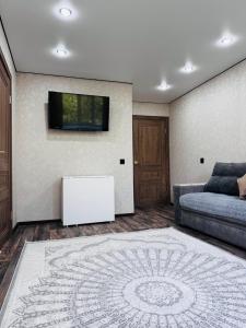 a living room with a couch and a tv on a wall at Квартира in Temirtaū