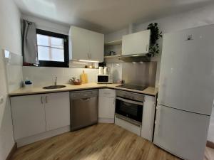 a kitchen with white cabinets and a white refrigerator at Jengina, muy centrico in Cadaqués