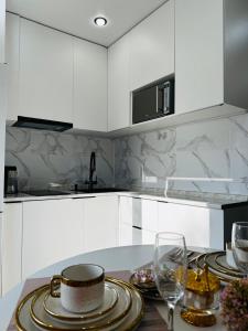 a white kitchen with a table with plates and wine glasses at Квартира in Temirtaū +13 photos