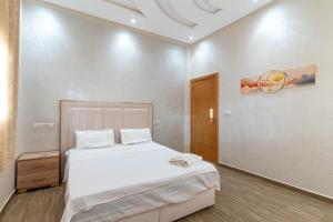 a bedroom with a large bed with white sheets at Petit-villa avec piscine in Marrakesh