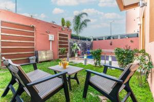 a patio with two chairs and a table in the grass at Petit-villa avec piscine in Marrakesh
