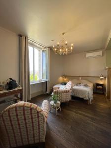 a bedroom with a bed and two chairs and a chandelier at A la terre ferme in Arnac-la-Poste