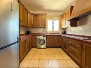 a kitchen with wooden cabinets and a washing machine at Villa Peñón View in Calpe