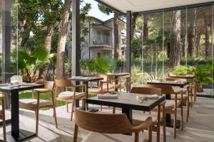a restaurant with tables and chairs and windows at Bolina Suite & Spa in Milano Marittima