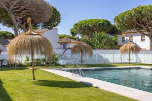 a house with a swimming pool and two straw umbrellas at Complejo Los Drogos in Novo Sancti Petri