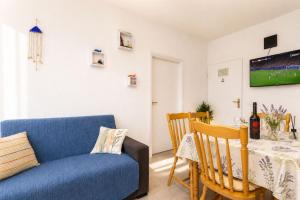 a living room with a table and a blue couch at Apartmani Bonaca in Pakoštane