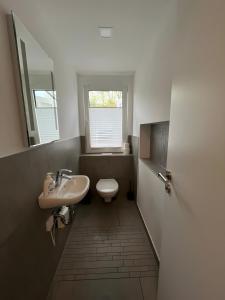 a bathroom with a sink and a toilet and a window at Ferienhaus Ahrenshoop in Ahrenshoop +11 photos
