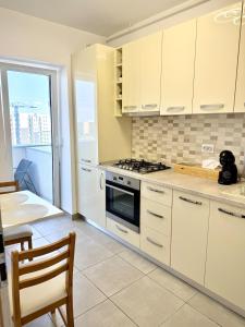 a kitchen with white cabinets and a table and a dining room at Contemporary Studio with Balcony - New Building in Bucharest