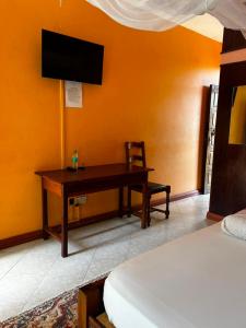 a bedroom with a desk and a tv on the wall at PRIMESHADE GUESTHOUSE in Malindi